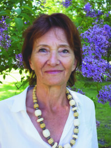 Porträtt av Kajsa Franchell med syrener i bakgrunden.